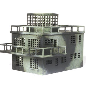 Könnte beinhalten: Ein grünes und graues Modell eines mehrstöckigen Gebäudes mit einem Dachbalkon und Geländern. Das Gebäude hat mehrere Fenster und einen kleinen Turm auf dem Dach.