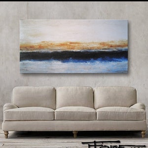 May include: Abstract painting on canvas with a horizontal band of blue, black, and orange. The painting is displayed on a wall above a beige sofa.