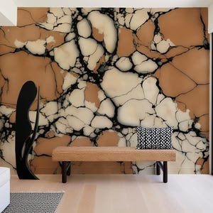 K&ouml;nnte beinhalten: Ein Wandbild mit einem gro&szlig;fl&auml;chigen Risssteinmuster in Beige-, Creme- und Schwarzt&ouml;nen. Eine rechteckige geflochtene Bank mit einem schwarz-wei&szlig; gemusterten Kissen steht vor der Wand, neben einer hohen, schwarzen, abstrakten Skulptur.