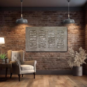 Op de afbeelding: Een grijze en witte abstracte kunstprint met een geometrisch patroon hangt aan een bakstenen muur in een woonkamer. De print is ingelijst en wordt verlicht door twee grijze hanglampen. Een grijze fauteuil staat in de hoek van de kamer, en een potplant staat in de hoek van de kamer.