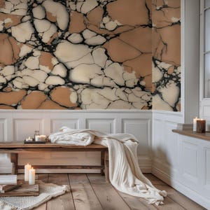 K&ouml;nnte beinhalten: Ein Innenraum mit einer Wand, die ein gro&szlig;fl&auml;chiges Risssteinmuster in Beige-, Creme- und Schwarzt&ouml;nen aufweist. Auf einer Holzbank liegt eine gefaltete wei&szlig;e Decke, w&auml;hrend brennende Kerzen auf einem Holztablett und dem Boden stehen.