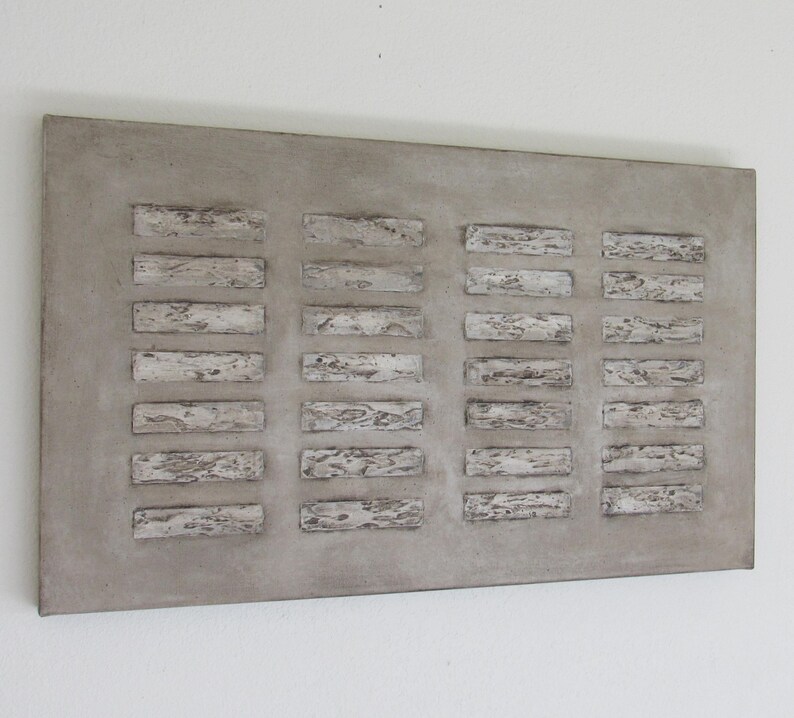 Op de afbeelding: Een rechthoekig grijs betonnen wandkunstwerk met een reli&euml;fpatroon van witte rechthoekige vormen.