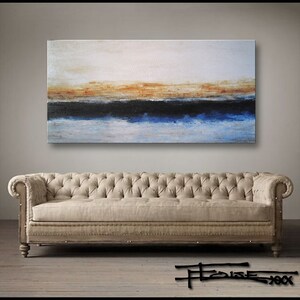 May include: Abstract painting with horizontal bands of white, orange, black, blue, and white. The painting is hanging on a wall above a beige sofa.