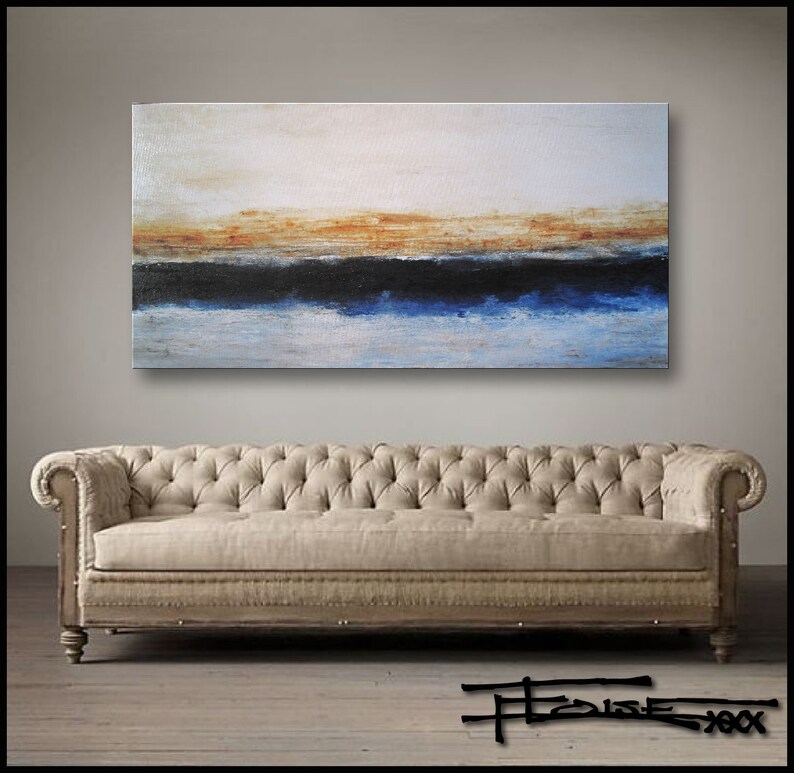 May include: Abstract painting with horizontal bands of white, orange, black, blue, and white. The painting is hanging on a wall above a beige sofa.