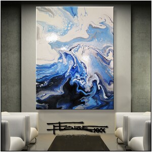May include: Abstract painting with swirling blue, white, and black paint. The painting has a glossy finish and is framed in a black frame.