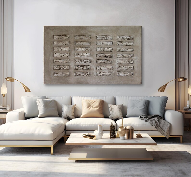 Op de afbeelding: Een groot abstract schilderij met een textuurrijke, grijze achtergrond en een patroon van rechthoekige vormen in grijstinten en wit. Het schilderij hangt aan een muur boven een witte hoekbank met kussens en een salontafel.