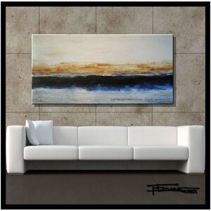 May include: Abstract painting with a horizontal band of blue, black, and brown across the middle of the canvas. The background is a light beige color. The painting is hanging on a wall above a white sofa.