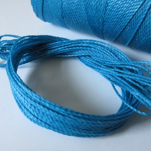 Könnte beinhalten: Nahaufnahme einer Spule mit leuchtend blauem Kordel. Der Kordel ist fest gewickelt und bereit für Bastelarbeiten oder andere Projekte.