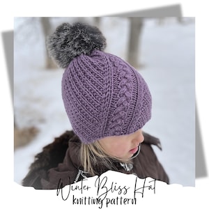 Könnte beinhalten: Lilafarbener Strickmütze mit Zopfmuster und einem Kunstfellbommel. Die Mütze wird von einem Kind in einer verschneiten Umgebung getragen. Strickmuster Winter Bliss Hat.