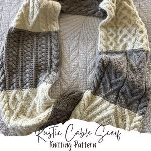 Könnte beinhalten: Ein gestrickter Rundschal mit abwechselnden Blöcken aus cremefarbenem und grauem Garn. Der Schal zeigt verschiedene strukturierte Zopfstrickmuster, einschließlich geflochtener und vertikaler Rippendesigns. Der Text "Rustic Cable Scarf Knitting Pattern" ist sichtbar.