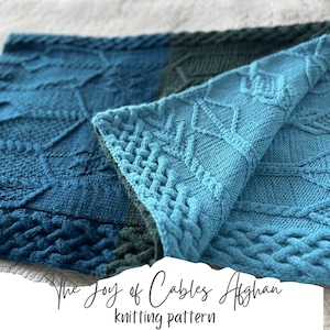 May include: A blue and green knitted blanket with a cable pattern. The blanket is folded in half and the text "The Joy of Cables Afghan knitting pattern" is visible in the bottom right corner.