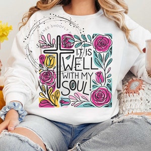 May include: White sweatshirt with a colorful graphic design featuring a cross, flowers, and the text "It is well with my soul!"