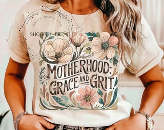 May include: A beige t-shirt with a floral design and the text "Motherhood: Grace and Grit".