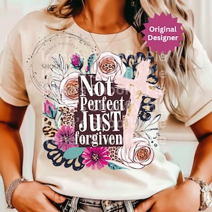 May include: Cream-colored t-shirt featuring a floral design with roses, a cross, and the text "Not Perfect Just Forgiven." The design includes pink, purple, and teal accents, with a leopard print detail. A "Original Designer" sticker is visible.