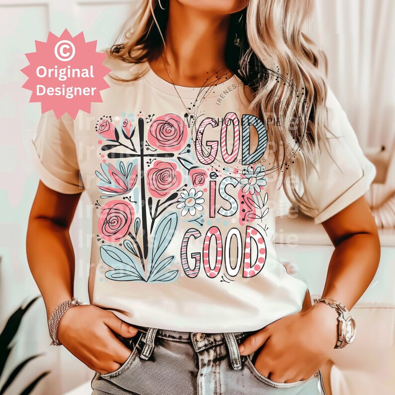 以下が含まれることがあります： 花柄のデザインと「God is good」という文字がピンク、ブルー、ブラックで書かれた白いTシャツです。