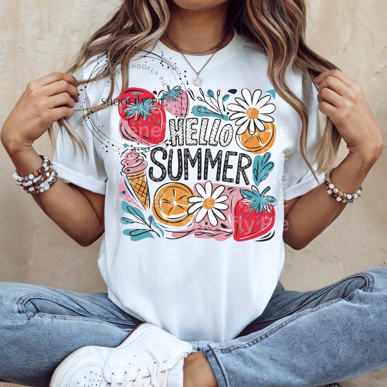 May include: White t-shirt with a colorful graphic design featuring strawberries, oranges, ice cream, and daisies. The text "Hello Summer" is printed in black.