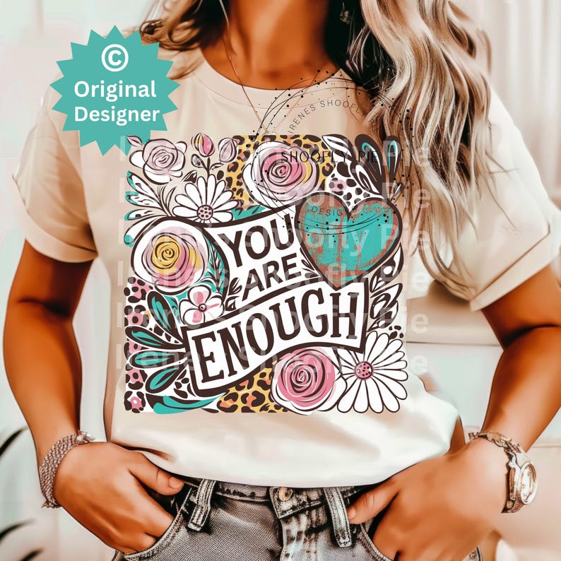 May include: A white t-shirt with a floral design and the text "You Are Enough" in black lettering. The design also includes a heart with a turquoise and brown pattern.