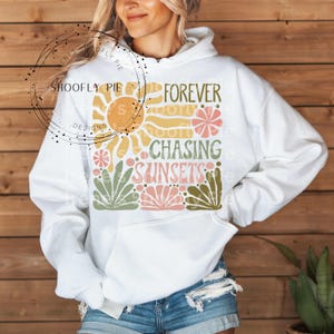May include: White hoodie with a graphic design featuring a sun, flowers, and the text "Forever Chasing Sunsets".
