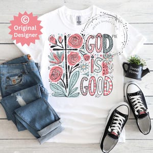 以下が含まれることがあります： 花柄のデザインと「God is Good」という文字が書かれた白いTシャツです。