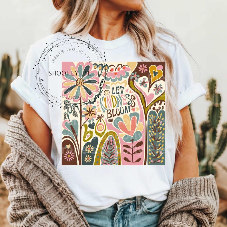 May include: White t-shirt with a colorful graphic design featuring flowers, hearts, and the text "Let Kindness Bloom".