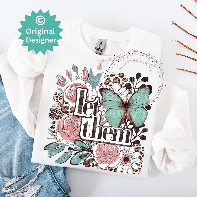 May include: White sweatshirt with a floral design, a butterfly, and the text "Let them" in black lettering.