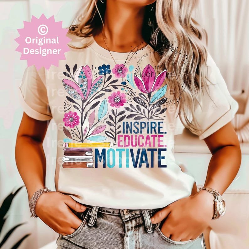 Op de afbeelding: Cr&egrave;mekleurig T-shirt met een bloemenontwerp met roze, blauwe en paarse bloemen. De woorden "INSPIRE. EDUCATE. MOTIVATE." staan onder een stapel boeken en een potlood. Het T-shirt heeft korte mouwen.