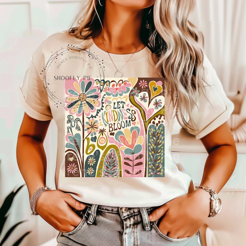 May include: White t-shirt with a colorful graphic design featuring flowers, hearts, and the text "Let Kindness Bloom".