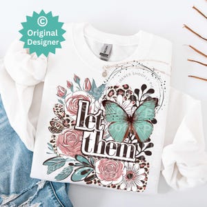 May include: White sweatshirt with a graphic design featuring a butterfly, flowers, and the text "Let them".