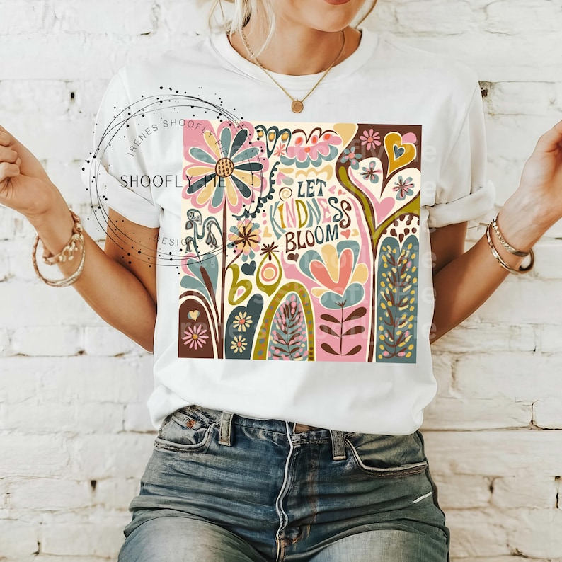 May include: White t-shirt with a colorful graphic design featuring flowers, hearts, and the text "Let Kindness Bloom".