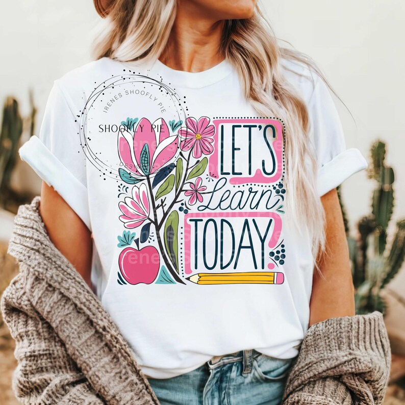 May include: White t-shirt with a colourful graphic design featuring flowers, an apple, and a pencil. The text "Let's Learn Today" is written in a playful font.