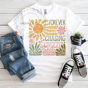 May include: White t-shirt with a graphic design featuring a sun, flowers, and the text "Forever Chasing Sunsets".