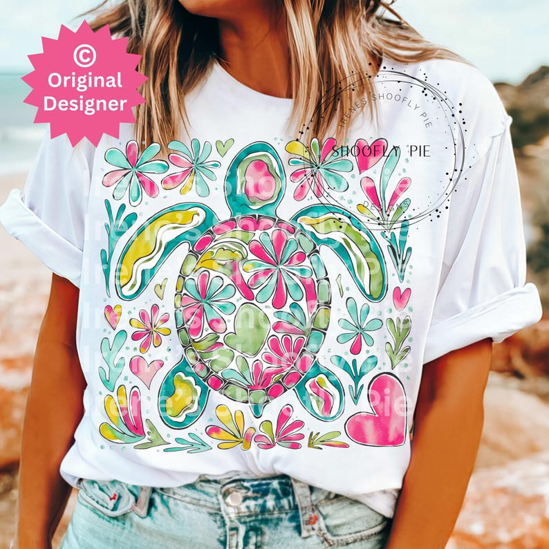 May include: White t-shirt with a colorful floral design featuring a sea turtle. The design includes pink, green, yellow, and blue flowers. The text "Shoofly Pie" is visible on the shirt.