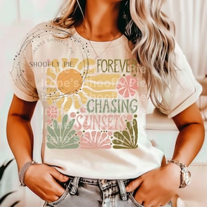 May include: A white t-shirt with a graphic design featuring a sun, flowers, and palm leaves. The text "Forever Chasing Sunsets" is printed on the shirt.