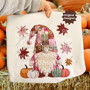 Op de afbeelding: Een crèmekleurig decoratief kussen met een herfstthema, met een kabouter met een lange witte baard en een patchwork hoed. Het kussen is versierd met pompoenen en herfstbladeren. De tekst "SHOOFly Pies" is zichtbaar.