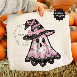 May include: A white Halloween-themed design featuring a ghost wearing a witch hat. The ghost has a floral pattern and pink lace trim. The hat is black with pink accents and a bow. The design includes the text "SHOOFly Pie Designs."