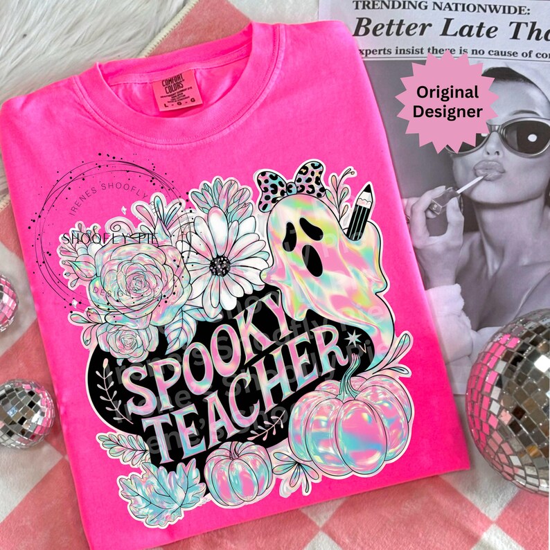 May include: A bright pink Comfort Colors sweatshirt featuring a floral and ghost design with the text "Spooky Teacher". The design includes pumpkins, flowers, and a ghost holding a pencil. The sweatshirt has a crew neck.