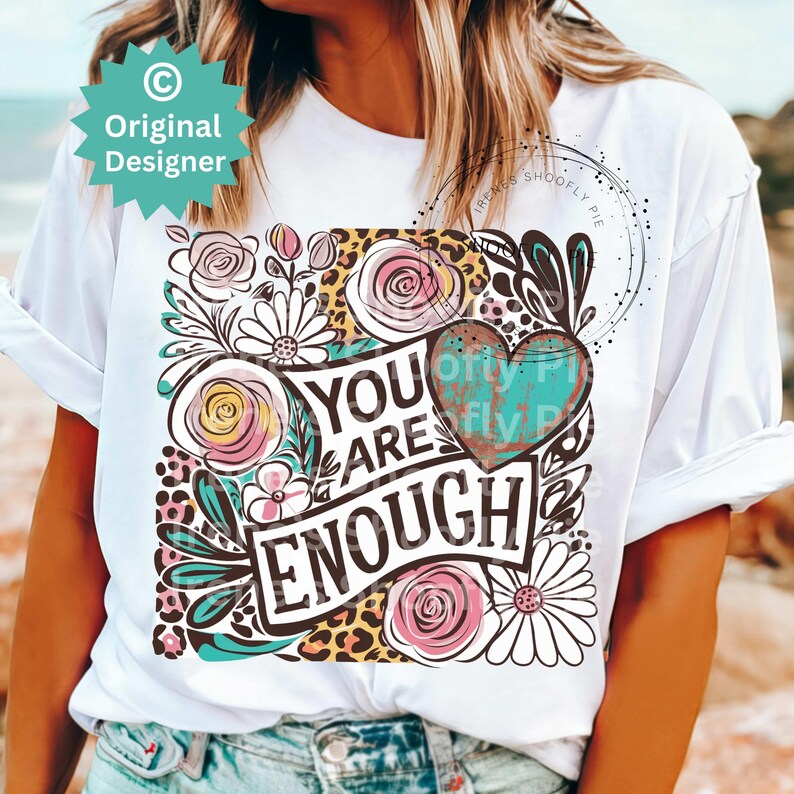 May include: White t-shirt with a colorful graphic design featuring flowers, leopard print, and the text "You Are Enough".