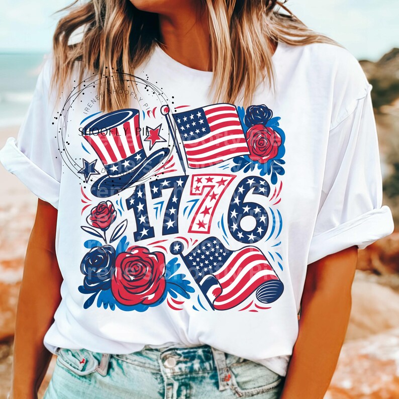 May include: White t-shirt with a red, white, and blue graphic design featuring a top hat, stars, flowers, and the number 1776.