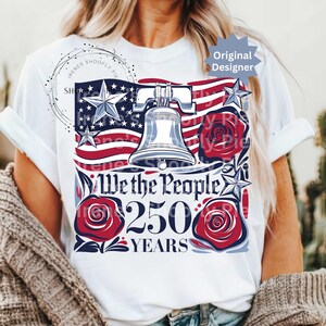 K&ouml;nnte beinhalten: Wei&szlig;es T-Shirt mit patriotischem Design. Das Design zeigt die amerikanische Flagge, die Liberty Bell, Sterne und rote Rosen mit dem Text "We the People 250 Years". Das Shirt hat einen Rundhalsausschnitt.