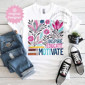 Op de afbeelding: Wit T-shirt met een bloemenontwerp in roze, blauw en zwart, en de woorden "INSPIRE. EDUCATE. MOTIVATE." De afbeelding bevat een blauwe spijkerbroek en zwart-witte sneakers. Een kleine zwarte gieter met "Sweet Home" is ook zichtbaar.