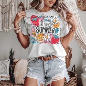 May include: A white t-shirt with a colorful graphic design featuring the text "Hello Summer" surrounded by strawberries, lemons, ice cream cones, and daisies.