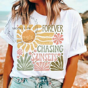 May include: White t-shirt with a graphic design featuring a sun, flowers, and the text "Forever Chasing Sunsets".