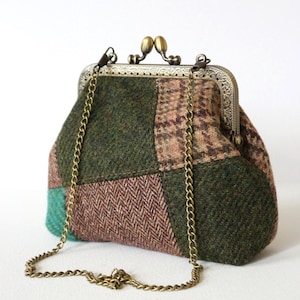 Peut inclure: Un sac à main en patchwork composé de tissu façon laine dans des tons vert forêt, marron et beige avec des motifs chevrons et carreaux. Il présente une armature en métal couleur laiton vieilli avec un fermoir à cliquet et une bandoulière chaîne.