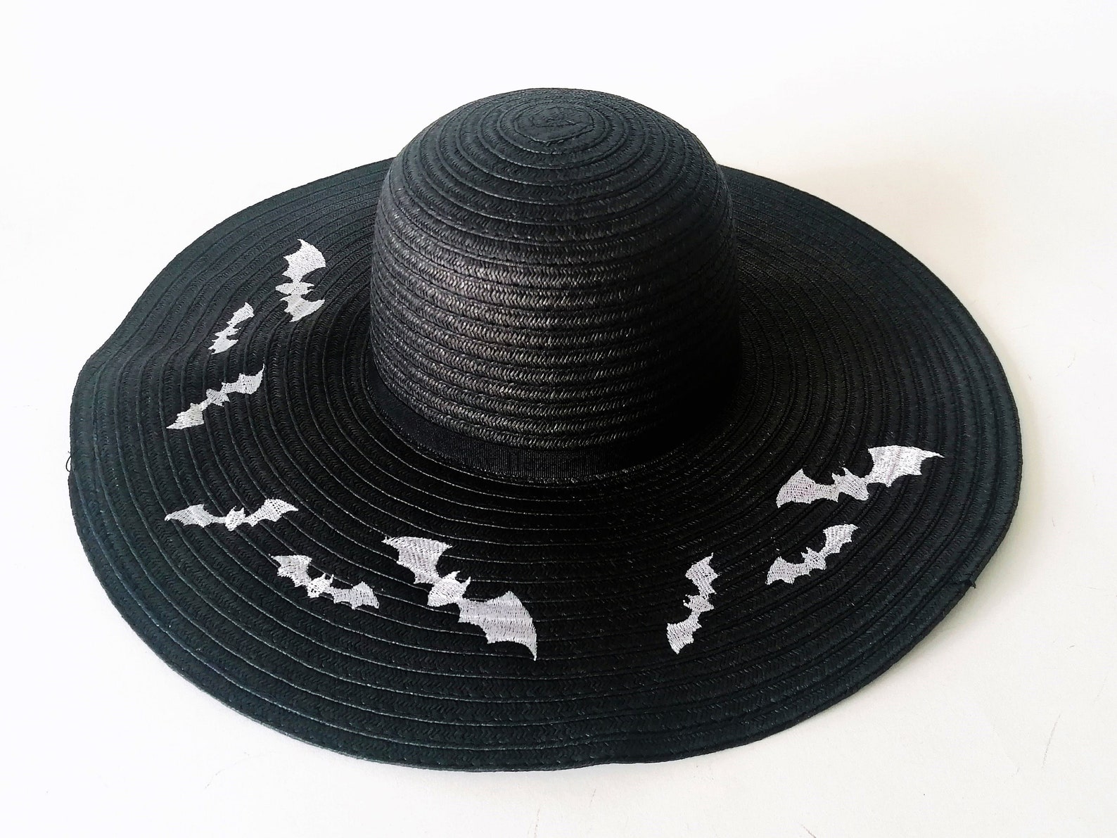 Black wide-brim sun hat with white embroidered bats, a spooky-chic accessory for summer goth beachwear looks.