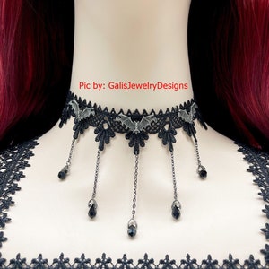 May include: Black lace choker necklace with silver bat charms and dangling black crystal beads.  "Pic by: GaliisJewelryDesigns" is printed on the image.