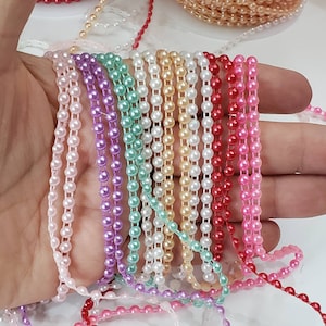 May include: Assortment of pearl trim in various colors, including pink, white, red, green, and purple. The trim is made of small, round beads strung together on a clear thread.