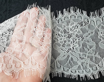 Peut inclure: Gros plan sur un tissu de dentelle blanche délicate avec des motifs floraux complexes. La dentelle a un bord festonné avec des franges. Le tissu est tenu, révélant sa transparence. Le fond est noir.