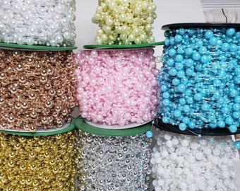 May include: Spools of beaded garland in various colors, including white, gold, silver, pink, and turquoise. The beads are strung together, creating a decorative chain. Ideal for crafts, decorations, and embellishments.