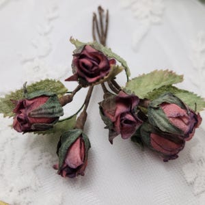 Pu&ograve; includere: Un grappolo di rose artificiali in varie tonalit&agrave; di bordeaux e rosa. Le rose hanno foglie verdi e steli marroni, creando un aspetto naturale. Ideale per lavori artigianali o decorativi. Ogni rosa misura circa 2 cm di diametro.
