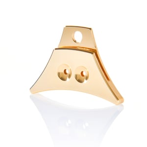 May include: A gold-colored dog whistle with two holes on the front. The whistle has a loop on the top for attaching to a lanyard.
